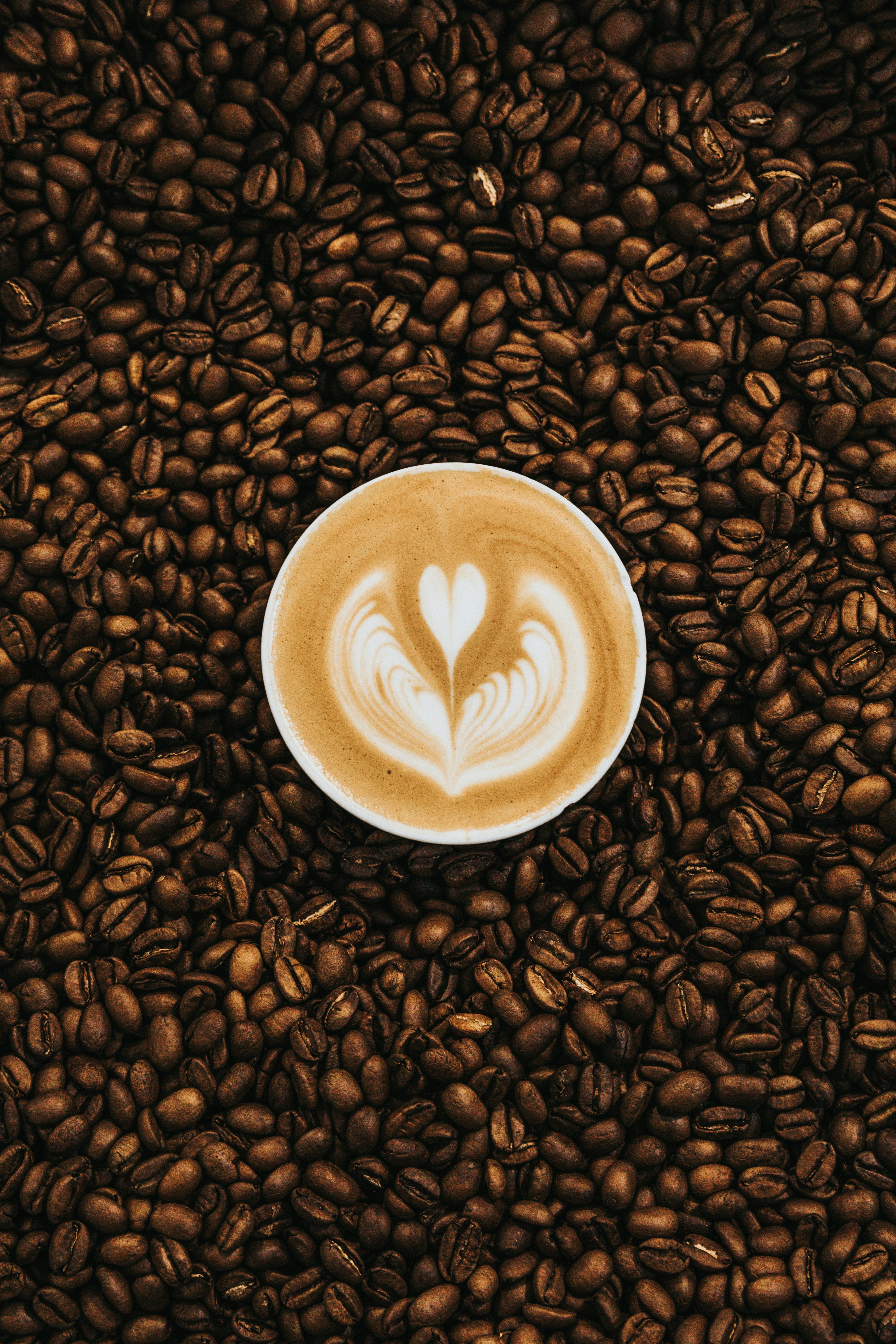 Šálek latte s latte art na kávových zrnech
